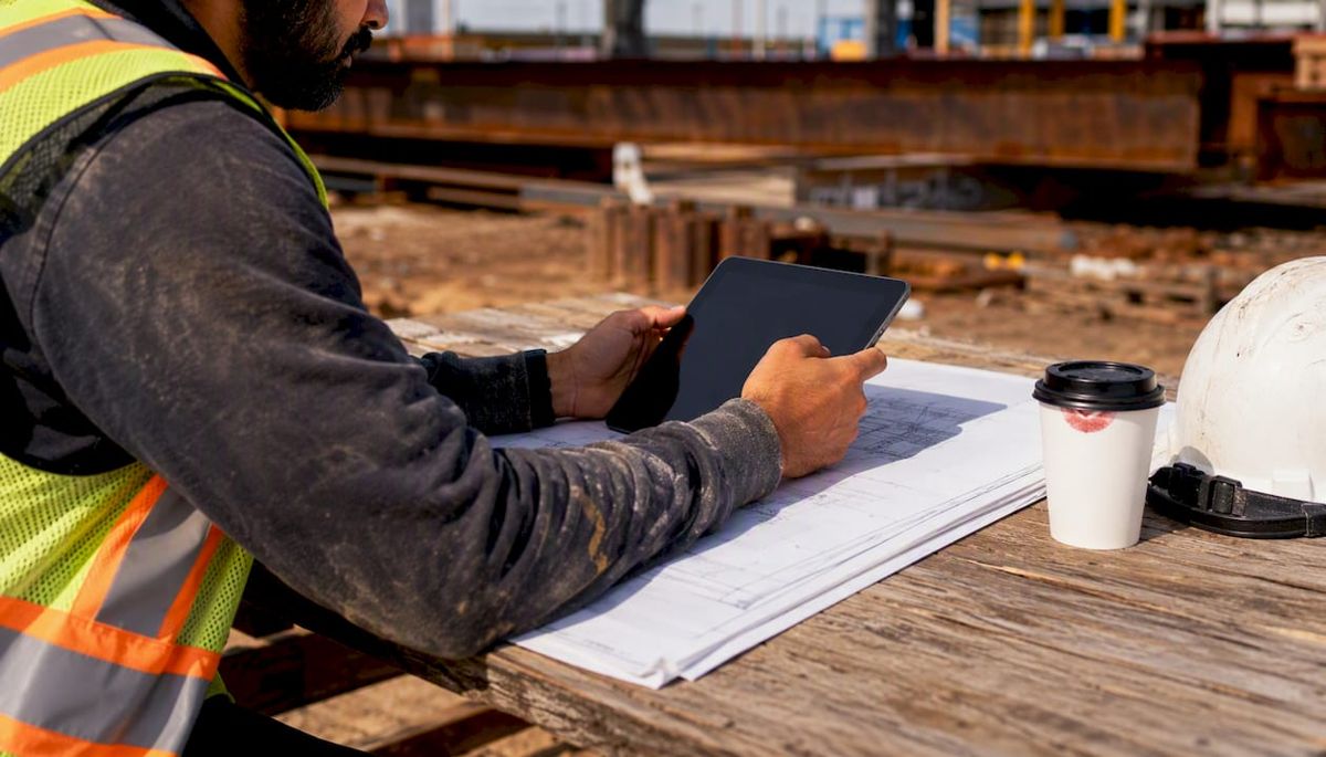 Subcontractor checking payment status outdoors on tablet